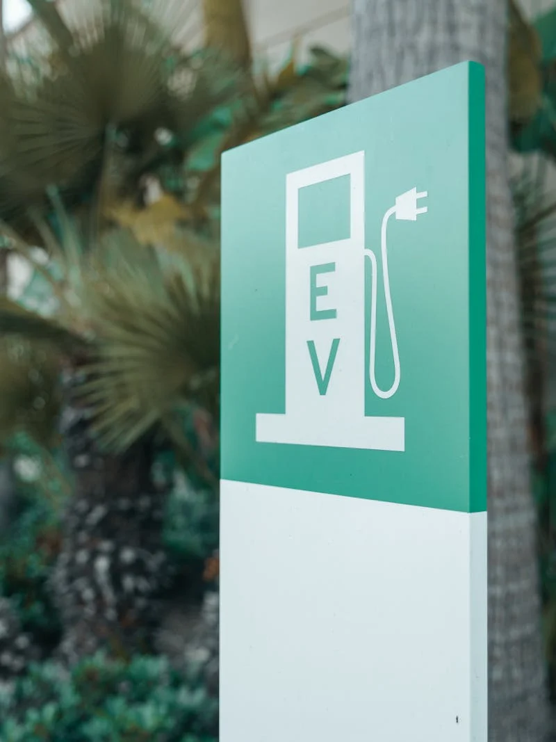 Green EV charging station sign with nature background